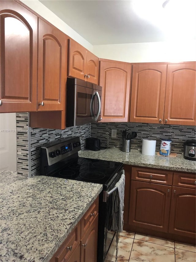 16700 NW 55th Ave Unit 12, Miami Gardens, FL 33055 - kitchen with range with electric stovetop, stainless steel microwave, light stone countertops, and decorative backsplash