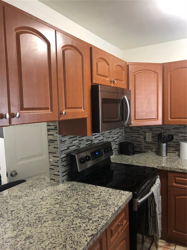 16700 NW 55th Ave Unit 12, Miami Gardens, FL 33055 - kitchen with appliances with stainless steel finishes, light stone countertops, backsplash, and brown cabinets