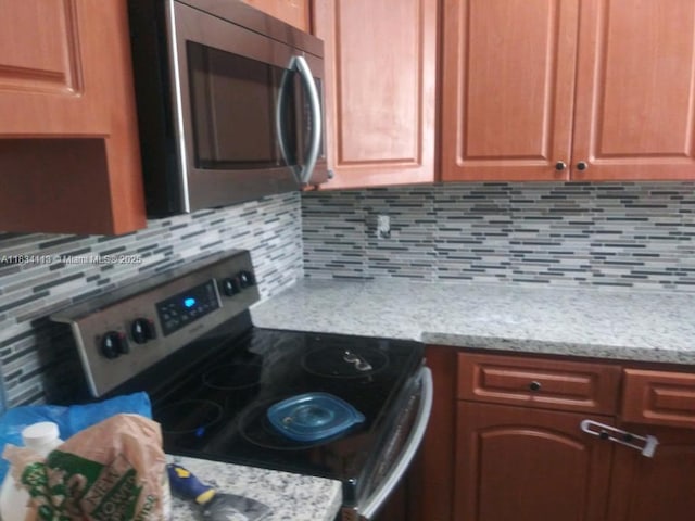 16700 NW 55th Ave Unit 12, Miami Gardens, FL 33055 - kitchen featuring stainless steel appliances, decorative backsplash, and light stone counters