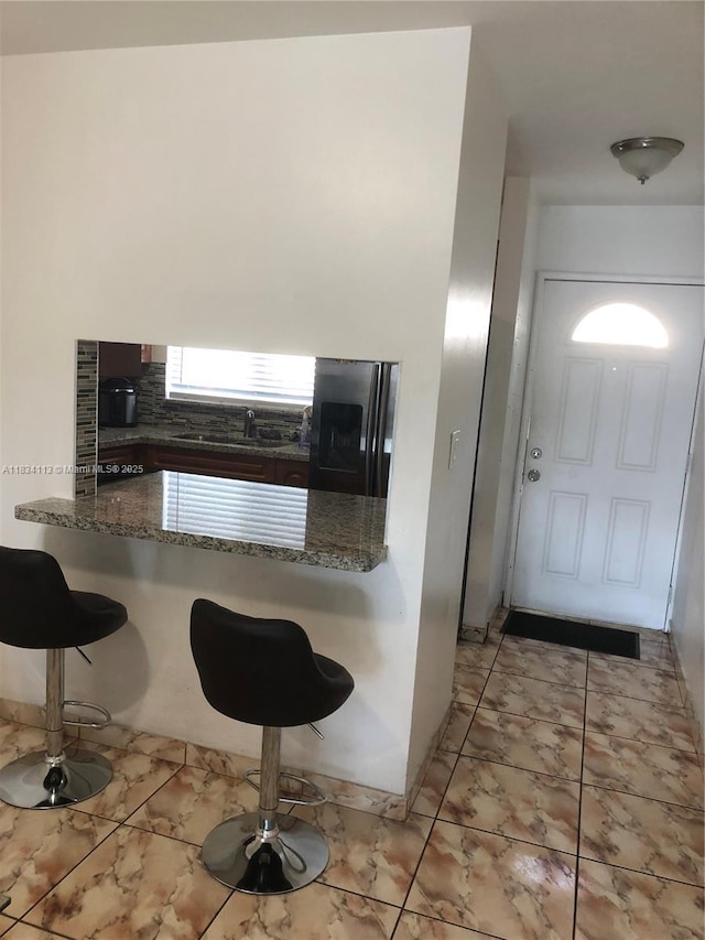 16700 NW 55th Ave Unit 12, Miami Gardens, FL 33055 - kitchen with smart refrigerator, a breakfast bar area, a peninsula, tasteful backsplash, and dark stone counters
