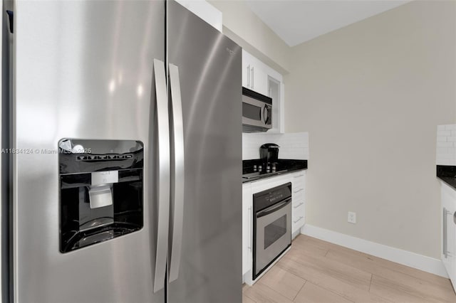 325 S Biscayne Blvd Unit 2816, Miami, FL 33131 - kitchen featuring appliances with stainless steel finishes, dark countertops, backsplash, white cabinetry, and light wood-style floors