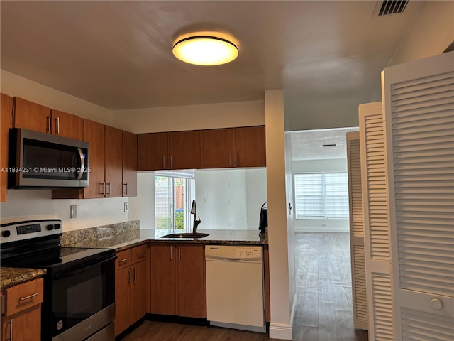 10234 NW 57th St, Doral, FL 33178 - kitchen featuring stainless steel appliances, dark wood-style floors, dark stone countertops, and brown cabinetry