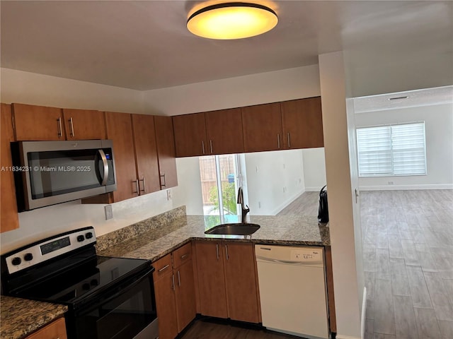 10234 NW 57th St, Doral, FL 33178 - kitchen with appliances with stainless steel finishes, wood finished floors, stone counters, and brown cabinets