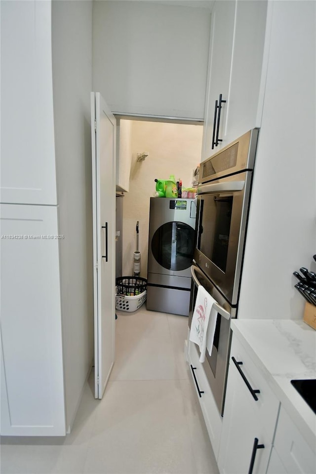 6293 SW 165th Ave, Miami, FL 33193 - kitchen featuring washer / clothes dryer, stainless steel double oven, white cabinets, and light stone counters