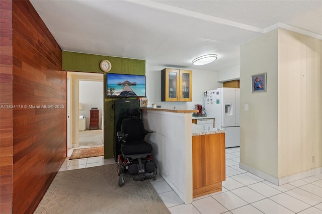 4350 Hillcrest Dr Unit 303, Hollywood, FL 33021 - kitchen with white fridge with ice dispenser, a peninsula, light tile patterned floors, glass insert cabinets, and wood walls