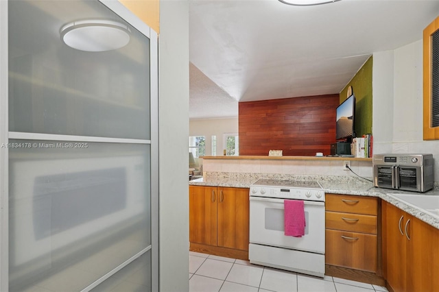 4350 Hillcrest Dr Unit 303, Hollywood, FL 33021 - kitchen with white electric range, brown cabinetry, light tile patterned flooring, and light stone countertops