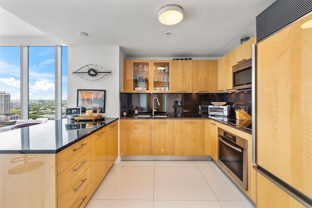 6899 Collins Ave Unit 2004, Miami Beach, FL 33141 - kitchen with appliances with stainless steel finishes, light tile patterned floors, healthy amount of natural light, glass insert cabinets, and a wall of windows