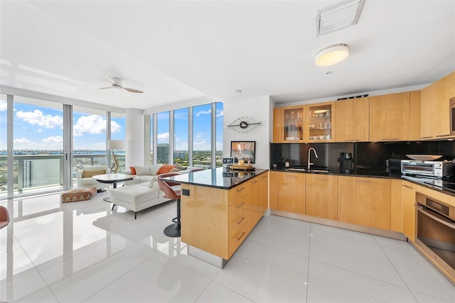 6899 Collins Ave Unit 2004, Miami Beach, FL 33141 - kitchen featuring a peninsula, expansive windows, dark countertops, glass insert cabinets, and stainless steel oven