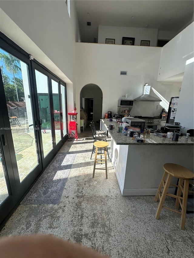 5900 NE 21st Ln, Fort Lauderdale, FL 33308 - kitchen with arched walkways, french doors, wall chimney exhaust hood, and a towering ceiling