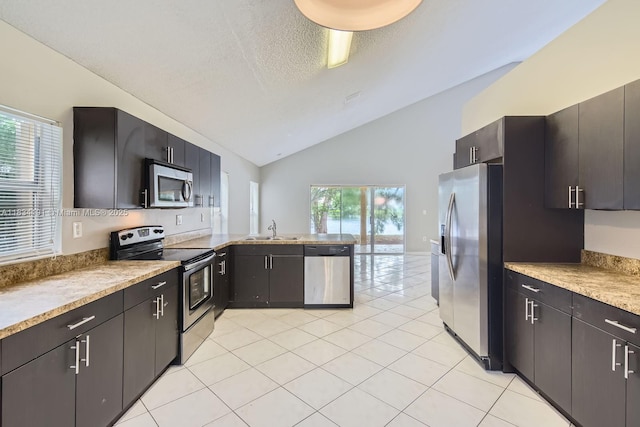 12700 SW 18th St, Miramar, FL 33027 - kitchen with stainless steel appliances, lofted ceiling, a peninsula, light tile patterned flooring, and a textured ceiling