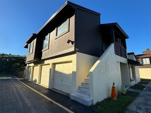 5344 Bosque Ln Unit 104, West Palm Beach, FL 33415 - view of side of property featuring a garage, stucco siding, and driveway