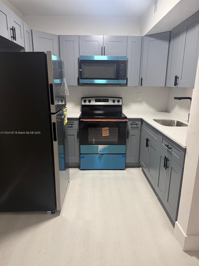 2225 W 53rd Pl Unit 2225, Hialeah, FL 33016 - kitchen with freestanding refrigerator, black electric range, stainless steel microwave, gray cabinets, and light countertops