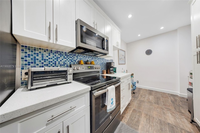 4330 Hillcrest Dr Unit 104, Hollywood, FL 33021 - kitchen featuring appliances with stainless steel finishes, tasteful backsplash, white cabinetry, recessed lighting, and light stone countertops