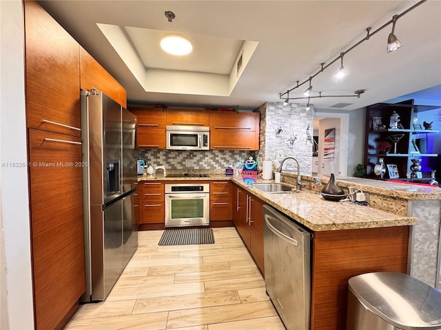 2641 N Flamingo Rd Unit 1203N, Sunrise, FL 33323 - kitchen with stainless steel appliances, a peninsula, brown cabinetry, backsplash, and a tray ceiling