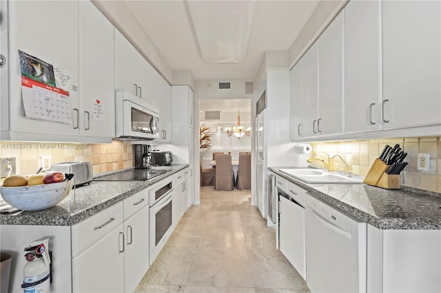 3200 N Ocean Blvd Unit 405, Fort Lauderdale, FL 33308 - kitchen with white appliances, a chandelier, decorative backsplash, and white cabinetry
