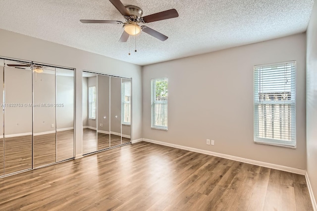 11035 NW 27th St, Sunrise, FL 33322 - unfurnished bedroom featuring two closets, a textured ceiling, wood finished floors, and a ceiling fan
