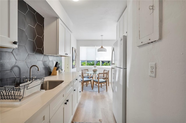 2380 NE 137th St, North Miami Beach, FL 33181 - kitchen featuring freestanding refrigerator, light wood-style floors, tasteful backsplash, white cabinets, and light countertops
