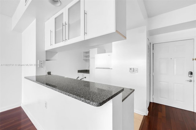 275 NE 18th St Unit 706, Miami, FL 33132 - kitchen featuring a peninsula, dark stone countertops, white cabinetry, and glass insert cabinets