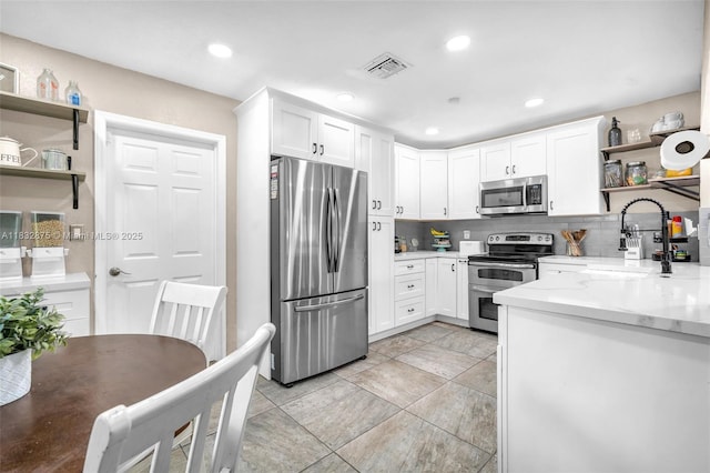 5820 Australian Pine Dr, Tamarac, FL 33319 - kitchen with appliances with stainless steel finishes, open shelves, white cabinets, tasteful backsplash, and light stone countertops