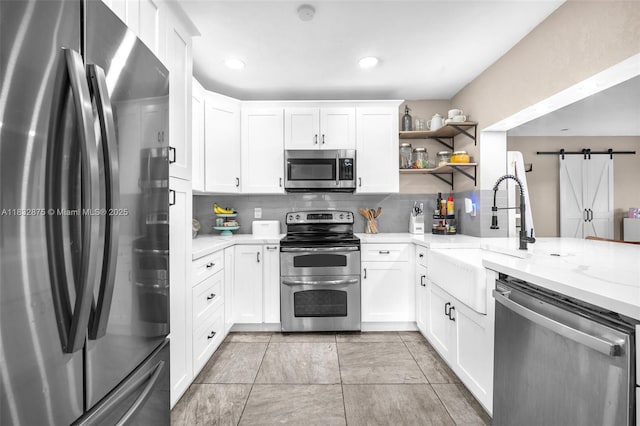 5820 Australian Pine Dr, Tamarac, FL 33319 - kitchen with stainless steel appliances, decorative backsplash, open shelves, white cabinets, and a barn door