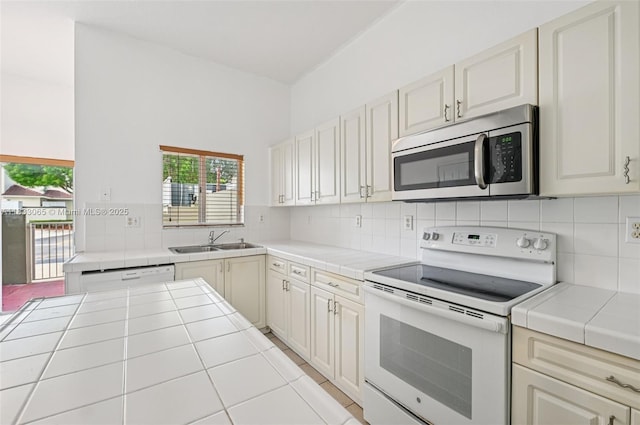 2456 SE 19th Ct, Homestead, FL 33035 - kitchen featuring white appliances, tile counters, backsplash, and light tile patterned floors