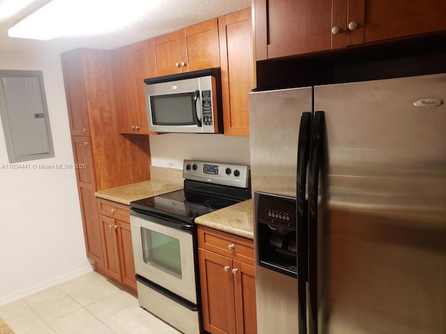 36 NW 6th Ave Unit 906, Miami, FL 33128 - kitchen with stainless steel appliances, electric panel, brown cabinetry, and light tile patterned floors
