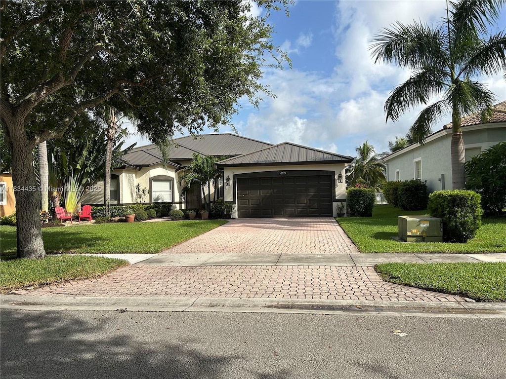 10975 NW 56th Ct, Coral Springs, FL 33076 - ranch-style home with decorative driveway, a garage, a front lawn, stucco siding, and a metal roof