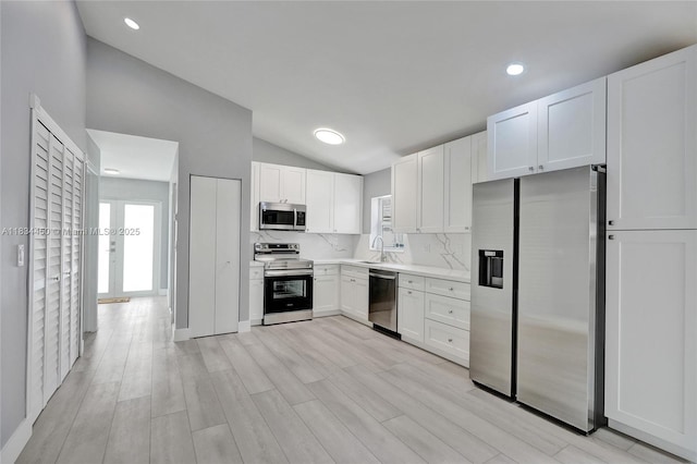2349 NW 34th Ave, Coconut Creek, FL 33066 - kitchen with stainless steel appliances, lofted ceiling, white cabinets, light countertops, and light wood-style flooring