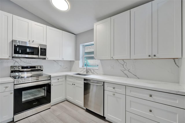 2349 NW 34th Ave, Coconut Creek, FL 33066 - kitchen with appliances with stainless steel finishes, vaulted ceiling, backsplash, white cabinets, and light stone countertops