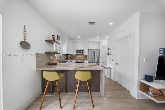 985 SW 147th Ct, Miami, FL 33194 - kitchen with appliances with stainless steel finishes, a peninsula, white cabinetry, open shelves, and a breakfast bar