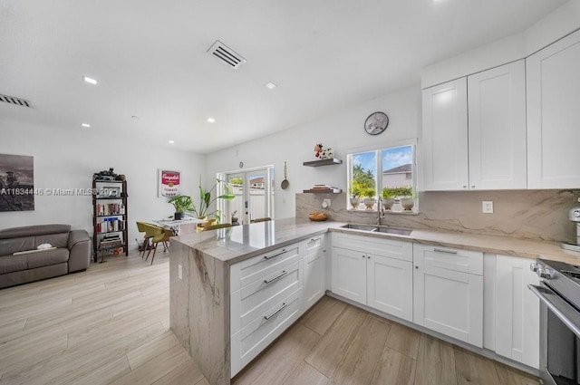 985 SW 147th Ct, Miami, FL 33194 - kitchen with stainless steel range, a peninsula, white cabinets, tasteful backsplash, and recessed lighting