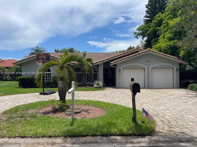 8140 NW 50th St, Coral Springs, FL 33067 - view of front facade featuring decorative driveway, an attached garage, a tiled roof, a front yard, and stucco siding