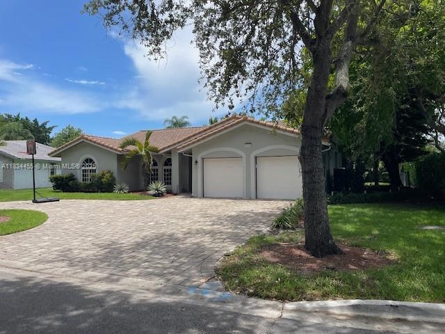8140 NW 50th St, Coral Springs, FL 33067 - view of front facade with a garage, decorative driveway, a front lawn, stucco siding, and a tile roof