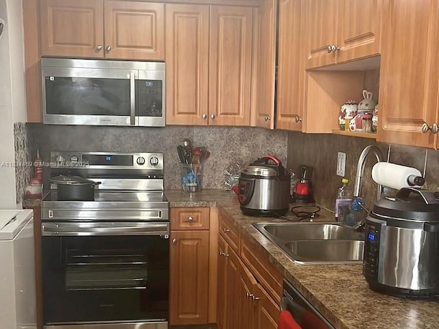 10090 NW 80th Ct Unit 1401, Hialeah Gardens, FL 33016 - kitchen with stainless steel appliances, decorative backsplash, dark countertops, washer / clothes dryer, and brown cabinetry