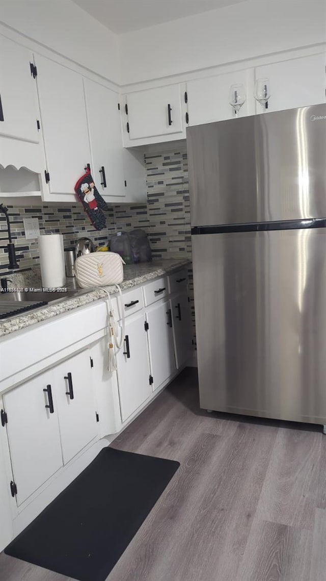 6137 Dewey St, Hollywood, FL 33023 - kitchen featuring freestanding refrigerator, wood finished floors, white cabinets, and decorative backsplash