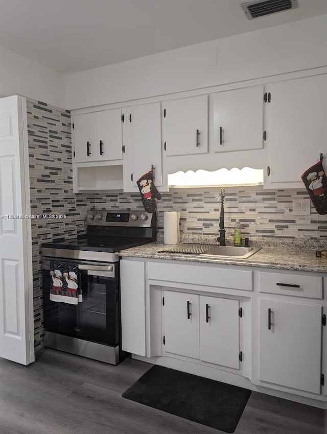 6137 Dewey St, Hollywood, FL 33023 - kitchen with stainless steel electric range oven, white cabinets, dark wood-type flooring, backsplash, and light stone countertops