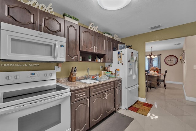 2175 NW 50th St, Miami, FL 33142 - kitchen with white appliances, dark brown cabinetry, a chandelier, light countertops, and light tile patterned flooring