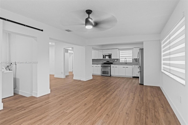 20620 Anchor Rd, Cutler Bay, FL 33189 - unfurnished living room with washer / dryer, a ceiling fan, light wood-type flooring, and a barn door