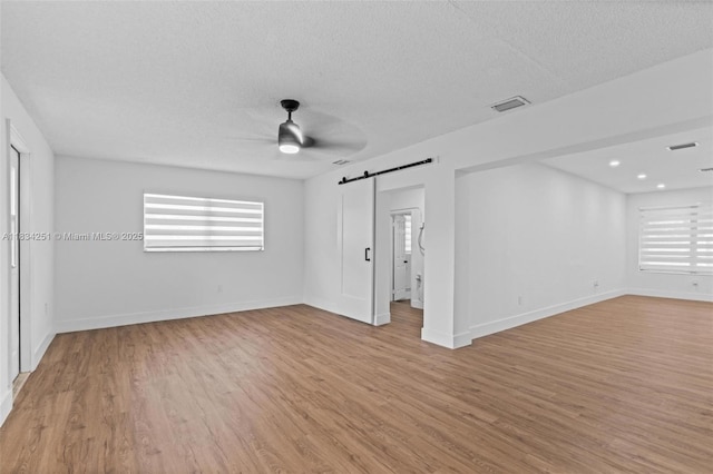 20620 Anchor Rd, Cutler Bay, FL 33189 - spare room with a barn door, a ceiling fan, healthy amount of natural light, light wood-style flooring, and a textured ceiling