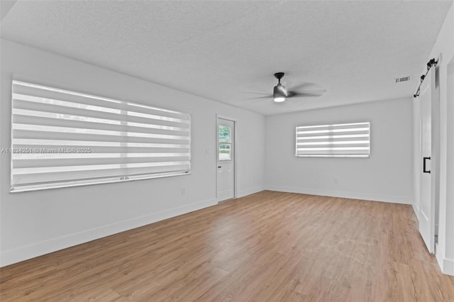 20620 Anchor Rd, Cutler Bay, FL 33189 - spare room featuring light wood-style flooring, ceiling fan, a barn door, and a textured ceiling