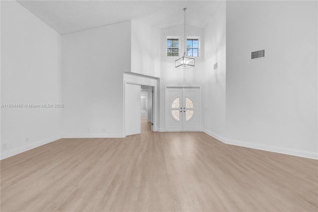 1525 Seabay Rd, Weston, FL 33326 - unfurnished living room with high vaulted ceiling, light wood-style flooring, a chandelier, and french doors