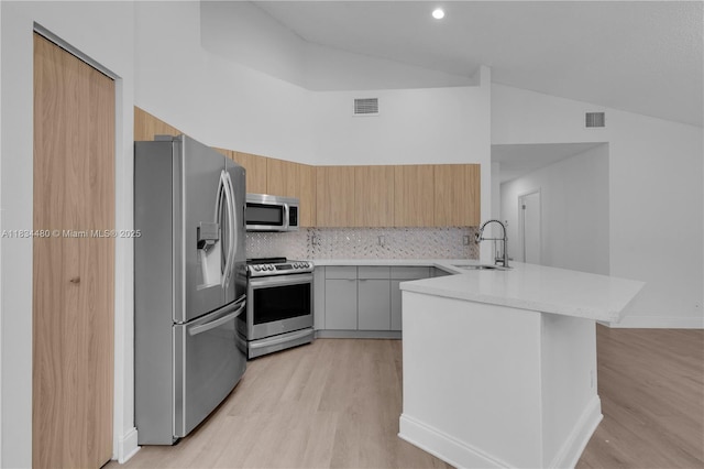 1525 Seabay Rd, Weston, FL 33326 - kitchen with appliances with stainless steel finishes, a peninsula, modern cabinets, light countertops, and light wood-style floors