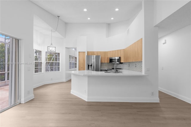 1525 Seabay Rd, Weston, FL 33326 - kitchen with appliances with stainless steel finishes, a towering ceiling, light countertops, light wood finished floors, and a peninsula