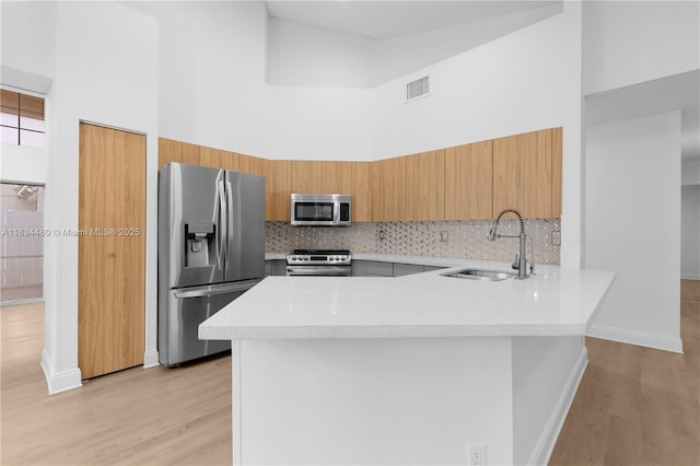 1525 Seabay Rd, Weston, FL 33326 - kitchen with stainless steel appliances, a high ceiling, a peninsula, light wood-style floors, and backsplash