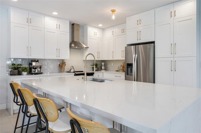 9932 NW 10th St, Miami, FL 33172 - kitchen featuring stainless steel fridge, wall chimney range hood, tasteful backsplash, white cabinetry, and a center island with sink