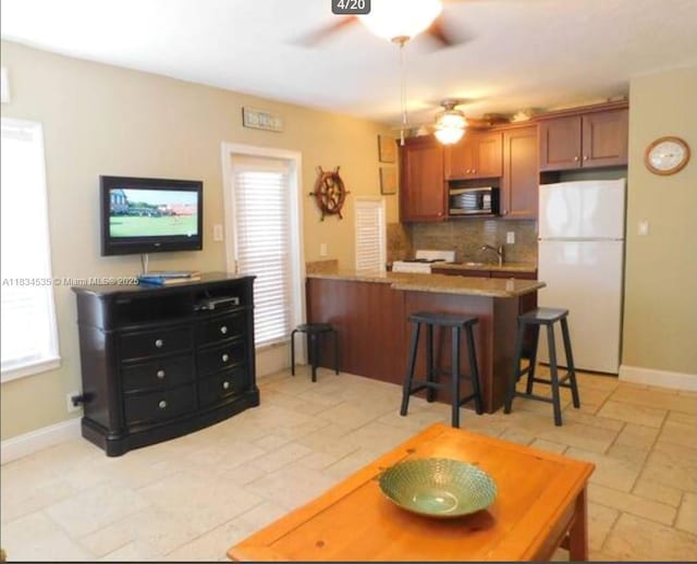310 Arthur St Unit 9, Hollywood, FL 33019 - kitchen featuring freestanding refrigerator, stainless steel microwave, ceiling fan, backsplash, and a peninsula