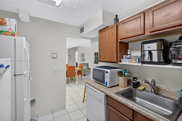 7745 SW 86th St Unit D-222, Miami, FL 33143 - kitchen with white appliances, light tile patterned floors, brown cabinets, light countertops, and a textured ceiling