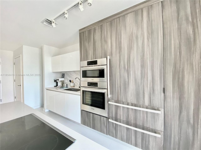 851 NE 1st Ave Unit 2802, Miami, FL 33132 - kitchen featuring black electric stovetop, modern cabinets, double oven, white cabinets, and light countertops