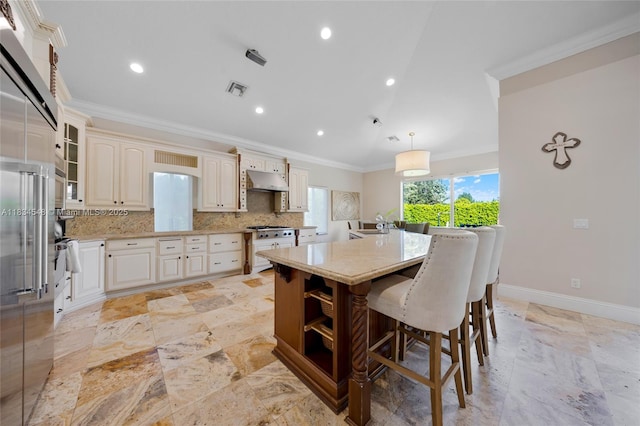 16701 SW 49th St, Southwest Ranches, FL 33331 - kitchen with crown molding, stone tile floors, a center island with sink, a breakfast bar area, and backsplash
