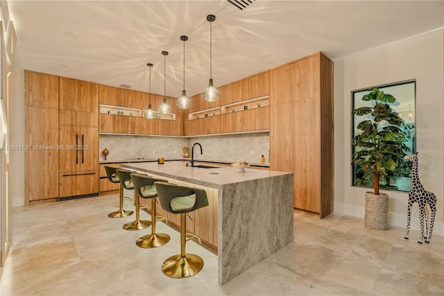 18269 SW 54th St, Miramar, FL 33029 - kitchen featuring modern cabinets, brown cabinetry, decorative light fixtures, a kitchen island with sink, and light stone counters